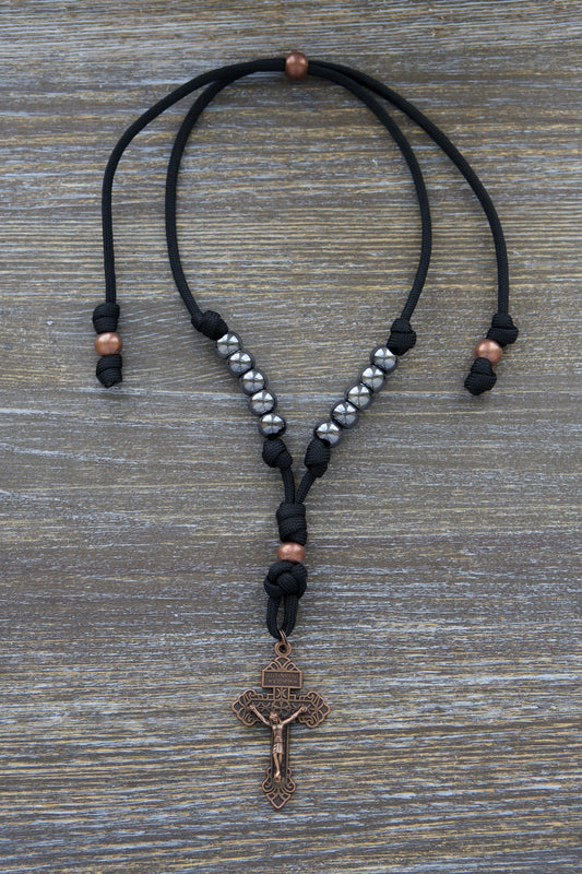 Black paracord and antique copper rearview mirror rosary, featuring gunmetal Hail Mary beads and a 2-inch antique copper Pardon Crucifix.
