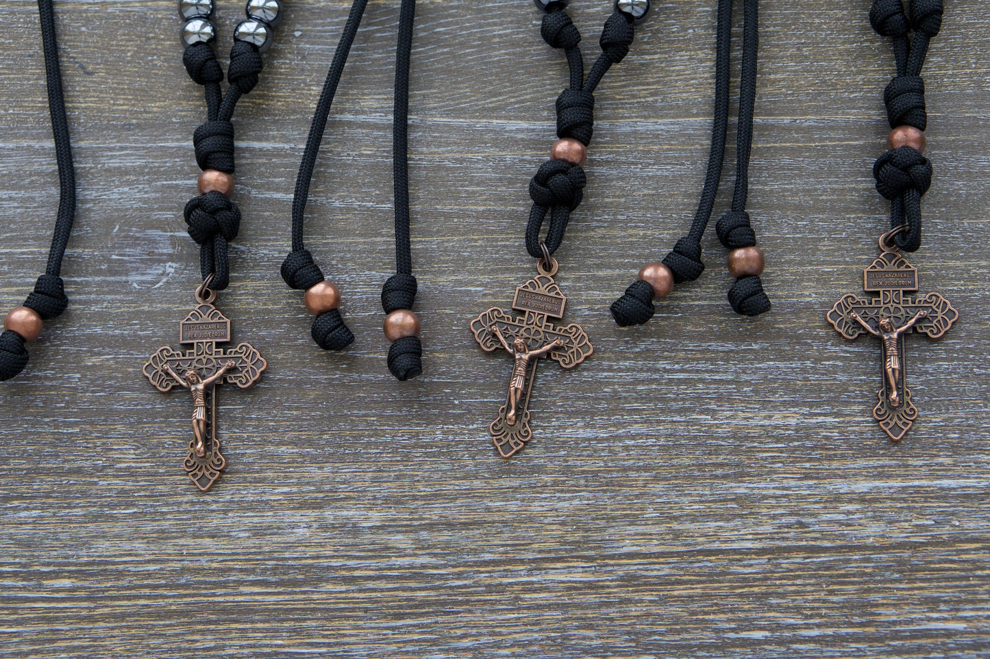 Black paracord and antique copper rearview mirror rosary featuring gunmetal Hail Mary beads and a 2-inch antique copper Pardon crucifix.