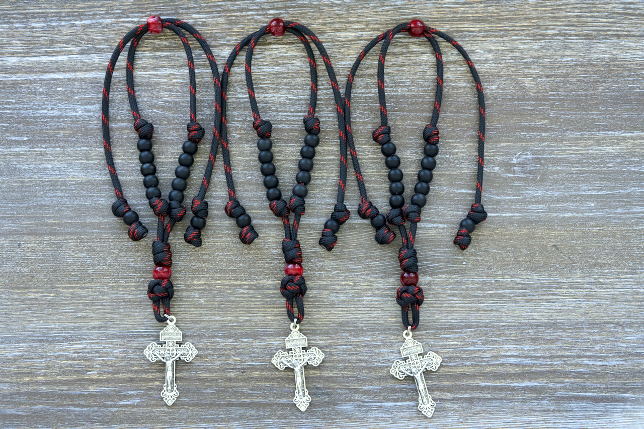 Blood of Christ Rearview Mirror Rosary - Elevate your prayer experience with this exquisite paracord mirror rosary, featuring a powerful combination of black and red rope, matte Hail Mary beads, and a striking silver Pardon Crucifix.