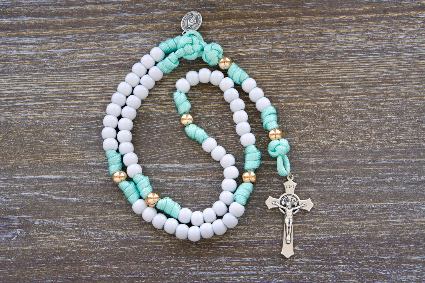 Sturdy mint green and white paracord rosary designed for children, featuring durable 10mm acrylic beads, a smaller Miraculous Medal, and a 2-inch St. Benedict crucifix.