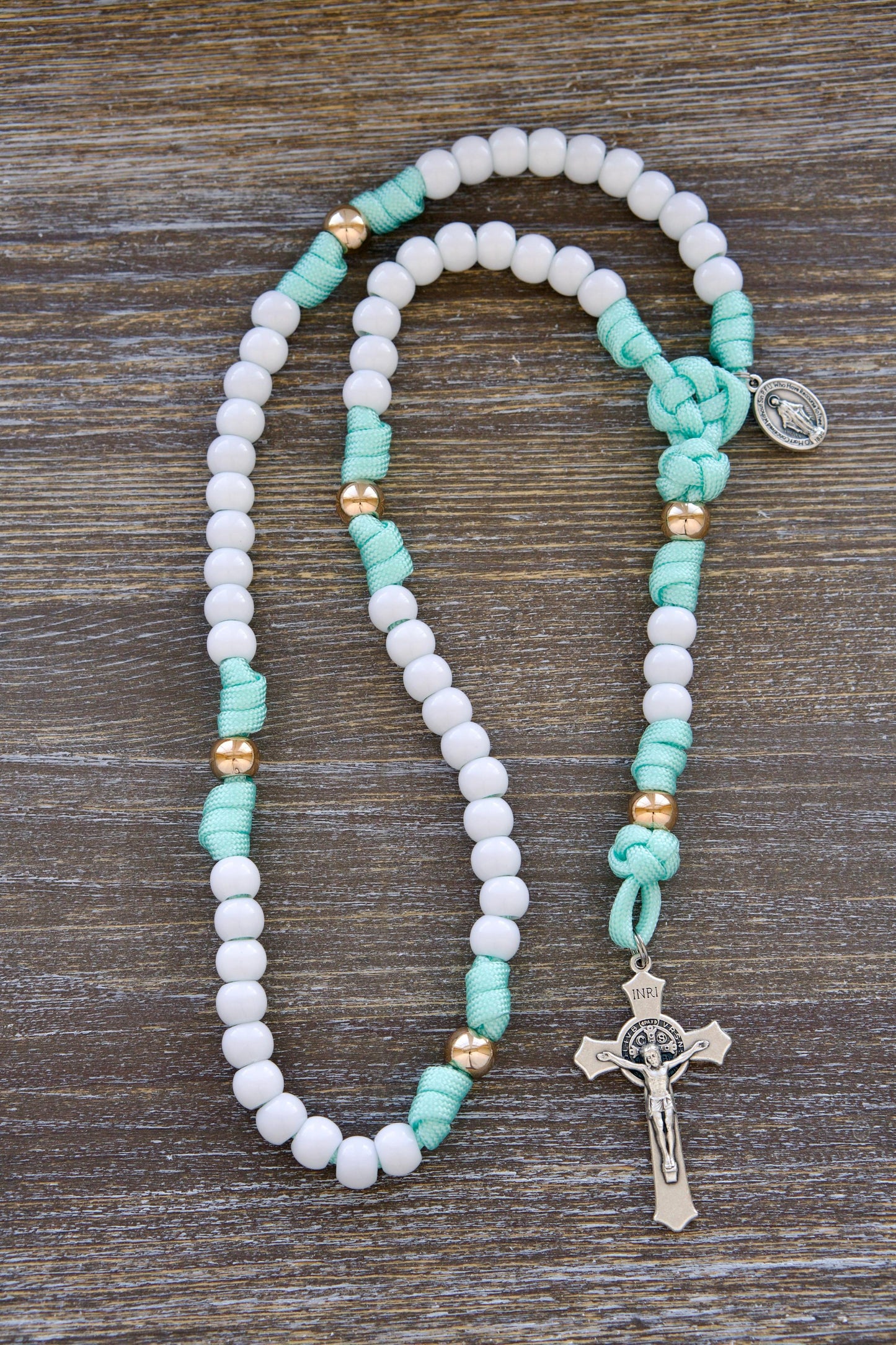 Children's Mint Green & White 5 Decade Paracord Rosary: Durable, kid-friendly rosary with mint green paracord, white Hail Mary beads, rose gold Our Father beads, smaller 10mm acrylic beads, and a miniature Miraculous Medal and St. Benedict crucifix.