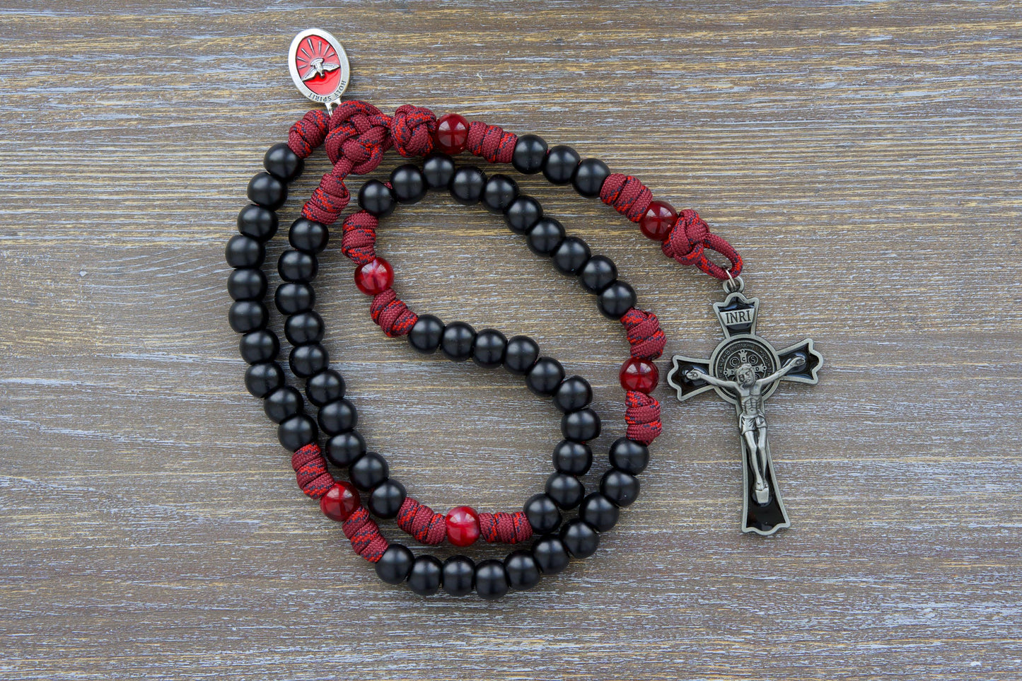 Crimson Shield - Holy Spirit Confirmation Rosary: A handcrafted 5-decade paracord rosary in rugged maroon red, featuring black or white Hail Mary beads, a gleaming enamel St. Benedict crucifix, and a vibrant red Holy Spirit medal.