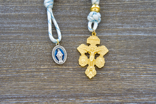 Divine Light Pocket Rosary: A handcrafted single decade rosary featuring white paracord 550 interwoven with blue accents, gold Our Father bead, exclusive 'miraculous blue' acrylic Hail Mary beads, a blue enamel Miraculous Medal, and a golden 'triple threat' pardon crucifix.
