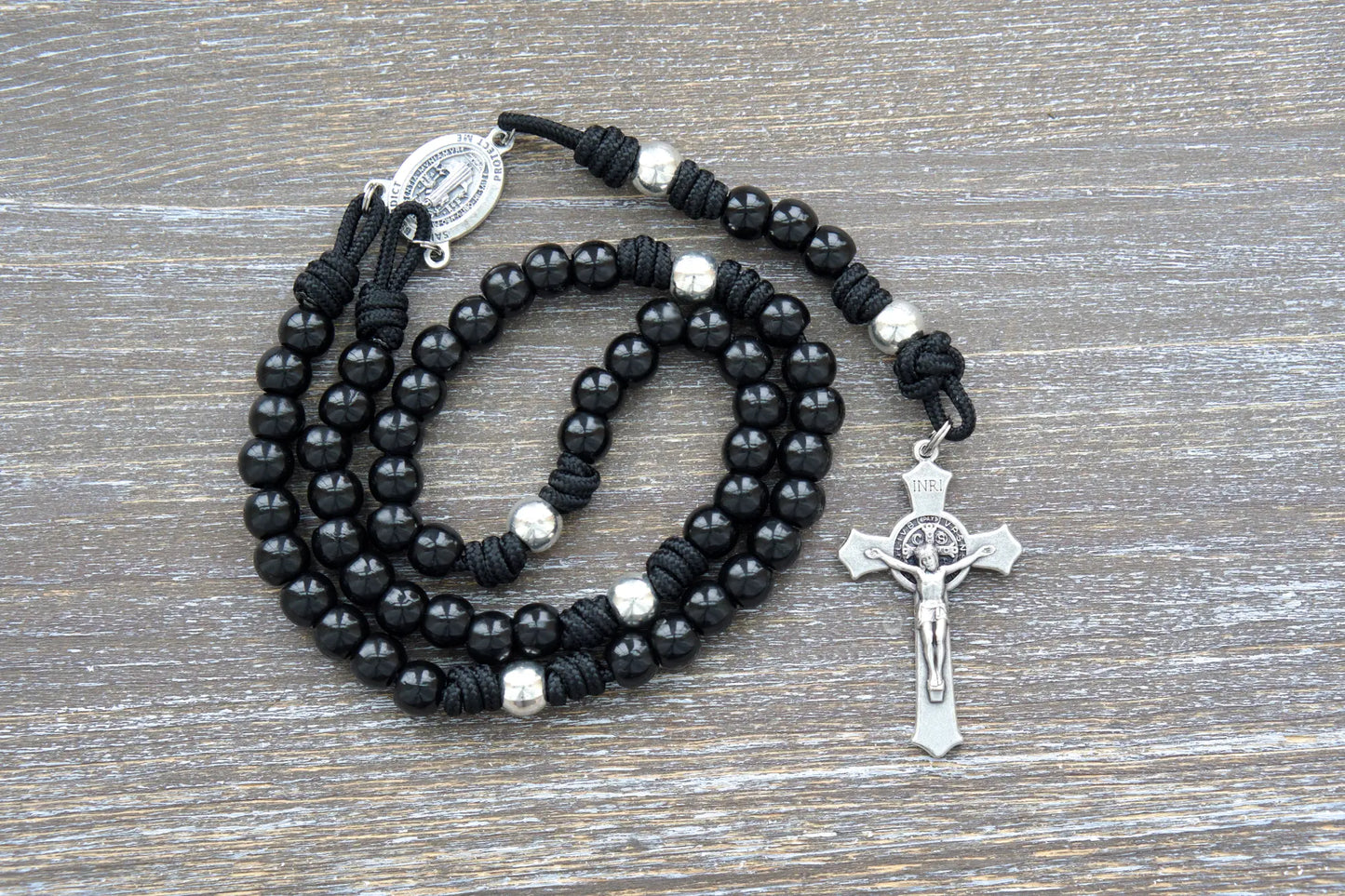 Premium metal alloy Hail Mary beads and silver Our Father beads on sturdy black paracord rosary, accented by a silver St. Benedict crucifix.