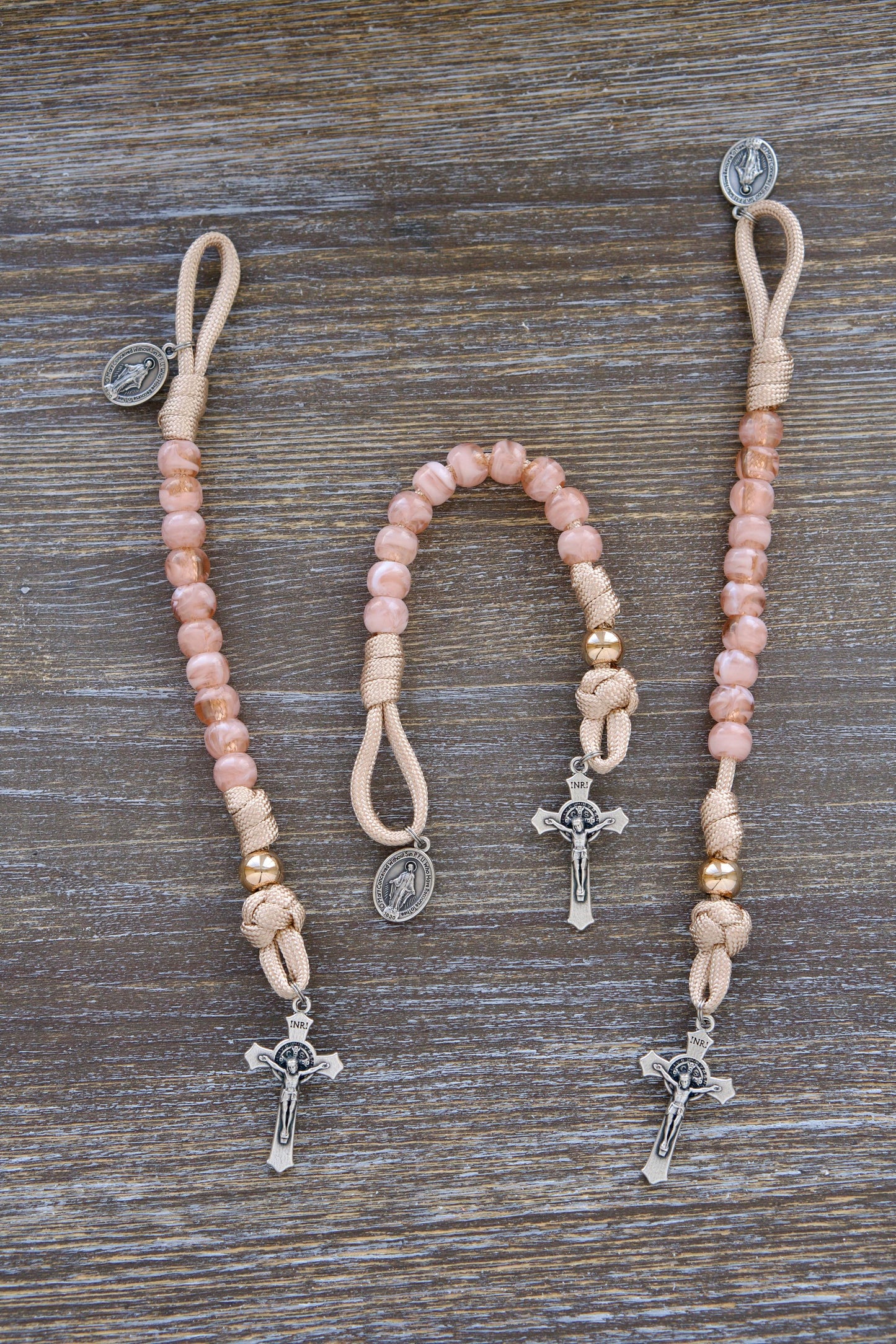 Gate of Heaven - Pocket Paracord Rosary: Close-up image showcasing rose-gold, tan, and milky pink paracord intertwined with 10mm acrylic Hail Mary beads and a shiny gold Our Father bead.