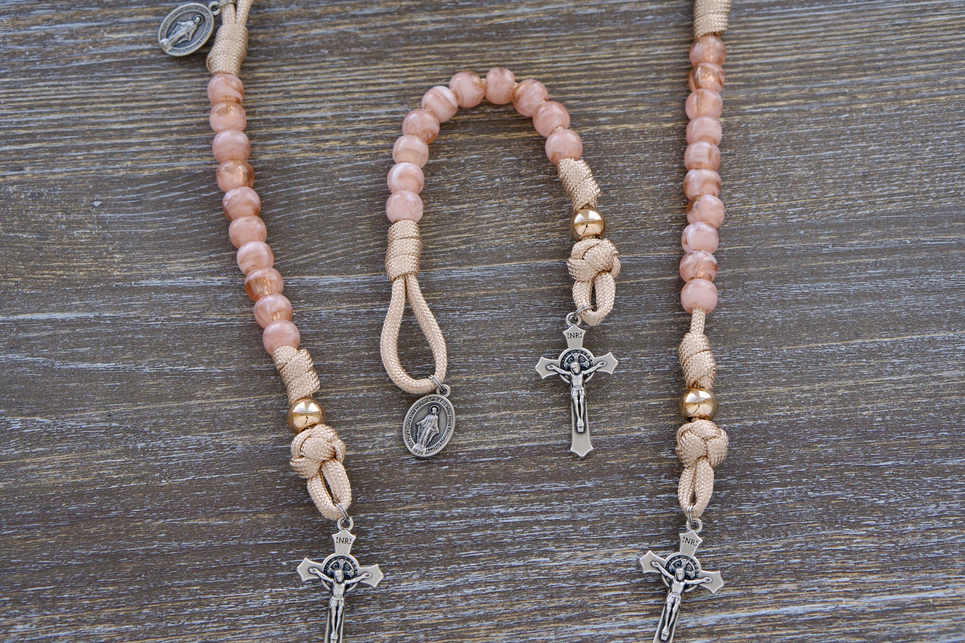 Handcrafted Gate of Heaven Pocket Rosary featuring rose-gold/tan paracord, milky pink Hail Mary beads, a shiny gold Our Father bead, and a smaller 3/4" Miraculous Medal. Designed for young Catholics, this durable and stylish rosary embraces traditional Catholic symbolism with a modern touch.