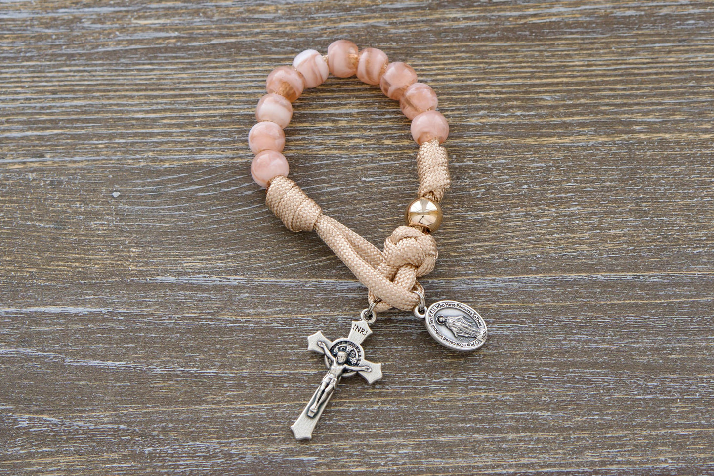 Pocket Paracord Rosary Gate of Heaven. Rose gold/tan paracord intertwined with milky pink Hail Mary beads and a shiny gold Our Father bead, featuring a 3/4 inch Miraculous Medal crucifix. Handmade by Sanctus Servo for young Catholics