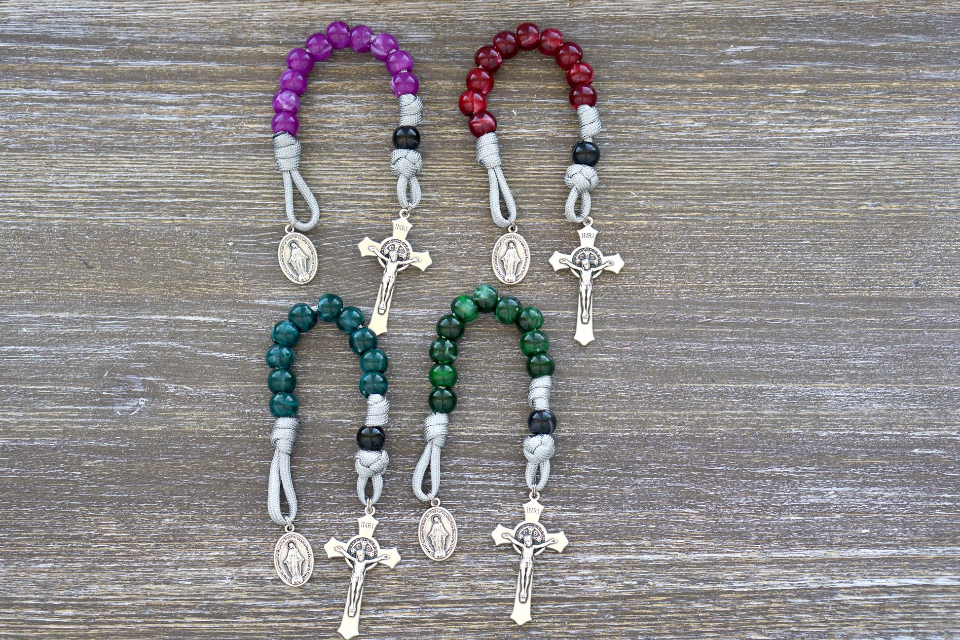 Gemstone Colored - 1 Decade Paracord Rosary, available in four beautiful colors - Garnet Red, Emerald Green, Ingolite Blue, and Magenta. Handcrafted with paracord 550, 12mm acrylic beads, Miraculous Medal devotional medal, and a 2-inch St. Benedict Crucifix for added spiritual strength.