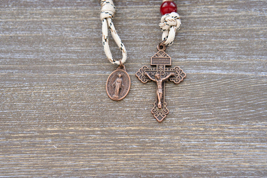 A handcrafted pocket paracord rosary, The Heavenly Rose, featuring durable brown/mocha acrylic Hail Mary beads, a maroon Our Father bead, and a striking tan paracord design.