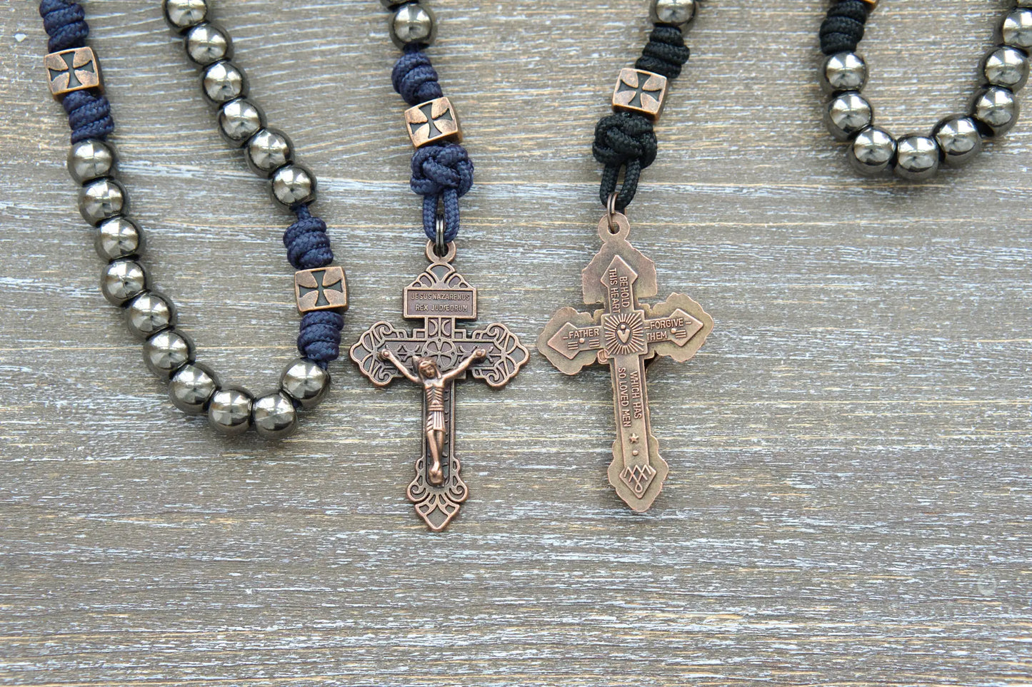 Black or navy blue paracord rosary featuring gunmetal Hail Mary beads, copper accents including a St. Michael centerpiece medal, and a Crucifix.
