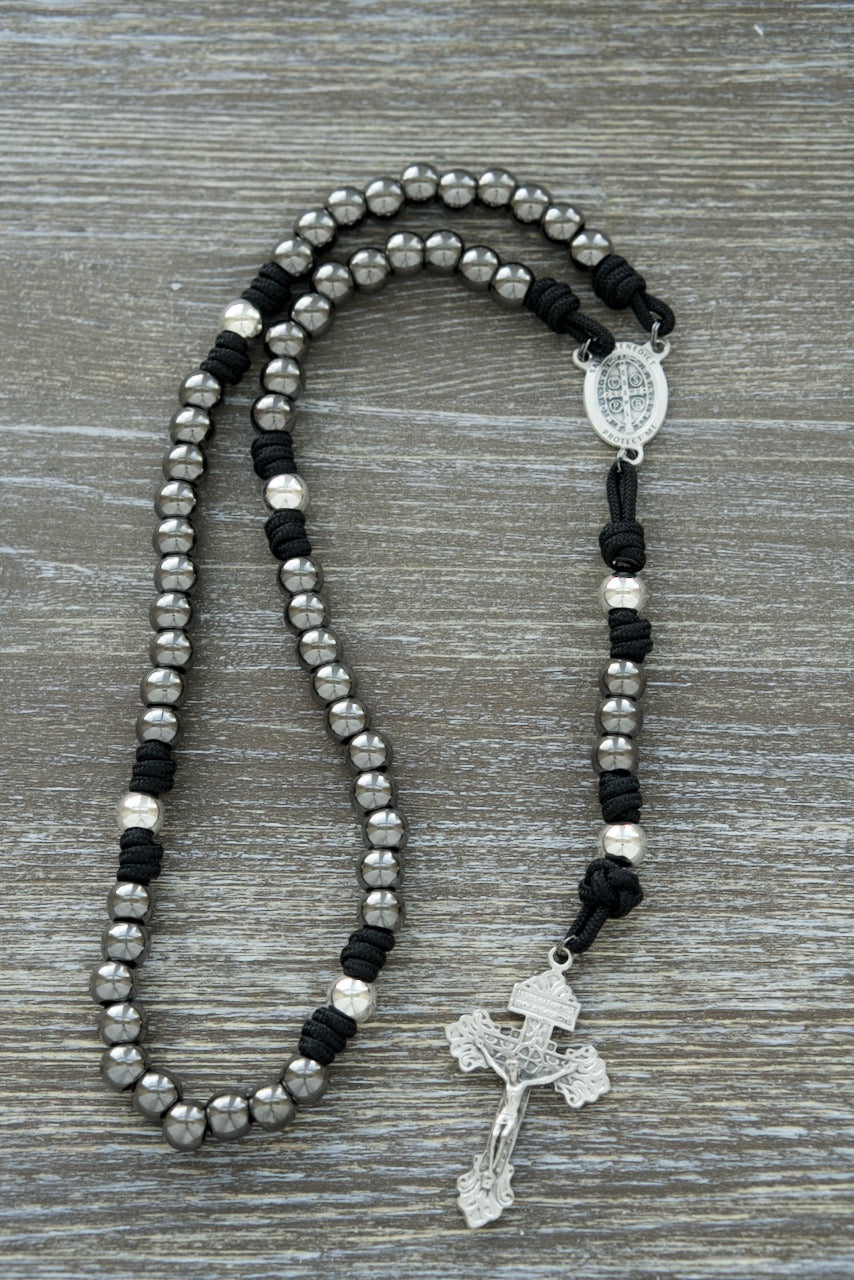 Iron Resolve Paracord Rosary: black paracord 275, gunmetal Hail Mary beads, silver Our Father beads, and St. Benedict medal.