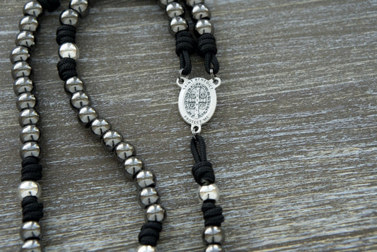 Embrace the power of your unwavering faith with our Iron Resolve - St. Benedict Paracord Rosary. This premium paracord rosary is crafted with durable black paracord 275 and stainless steel beads, symbolizing your strength and resilience in the face of life's challenges.