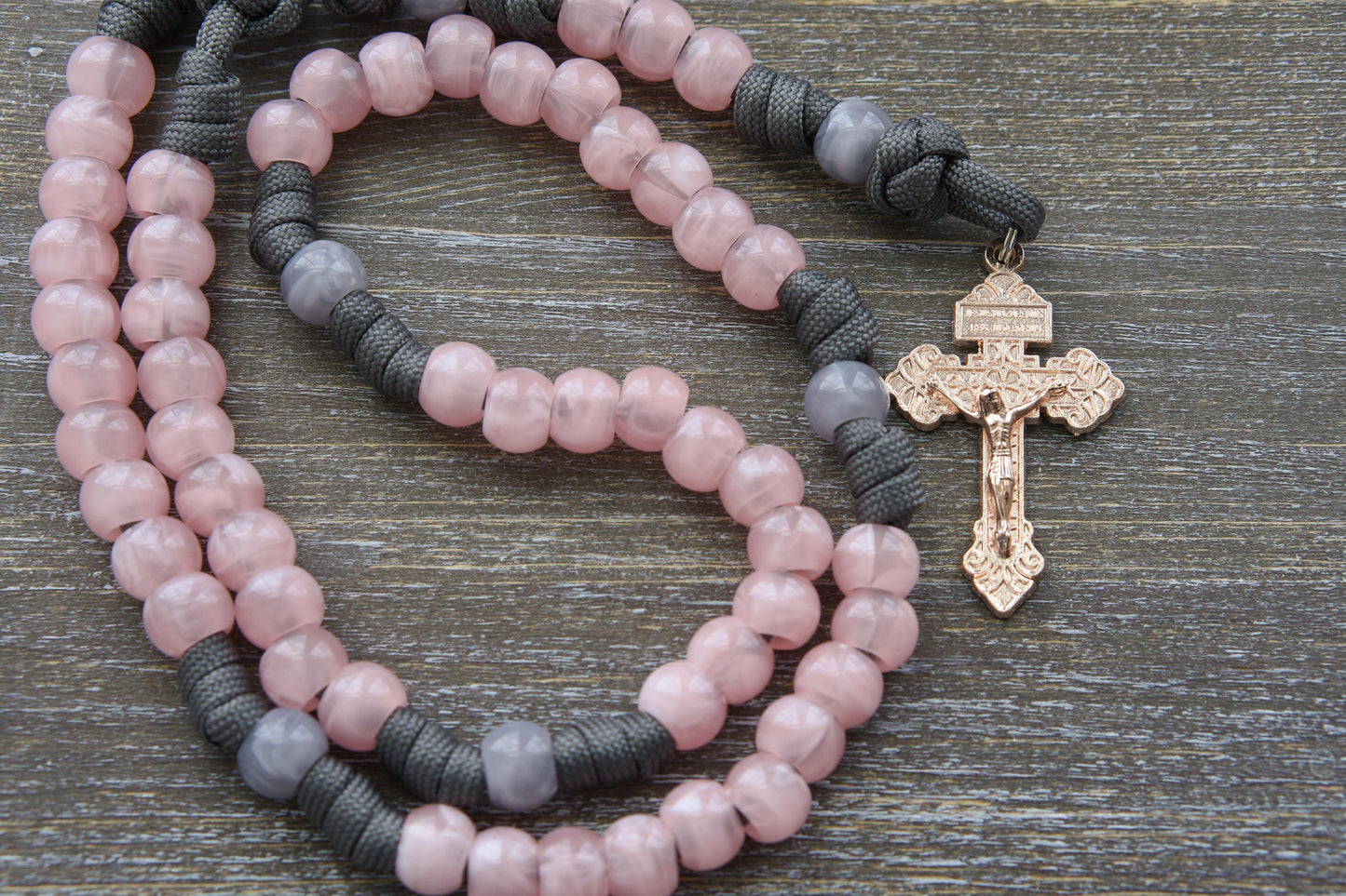 "Ite Ad Joseph" 5 Decade Paracord Rosary: A handcrafted, full-sized rosary featuring grey and milky pink paracord interwoven with acrylic Our Father and Hail Mary beads.
