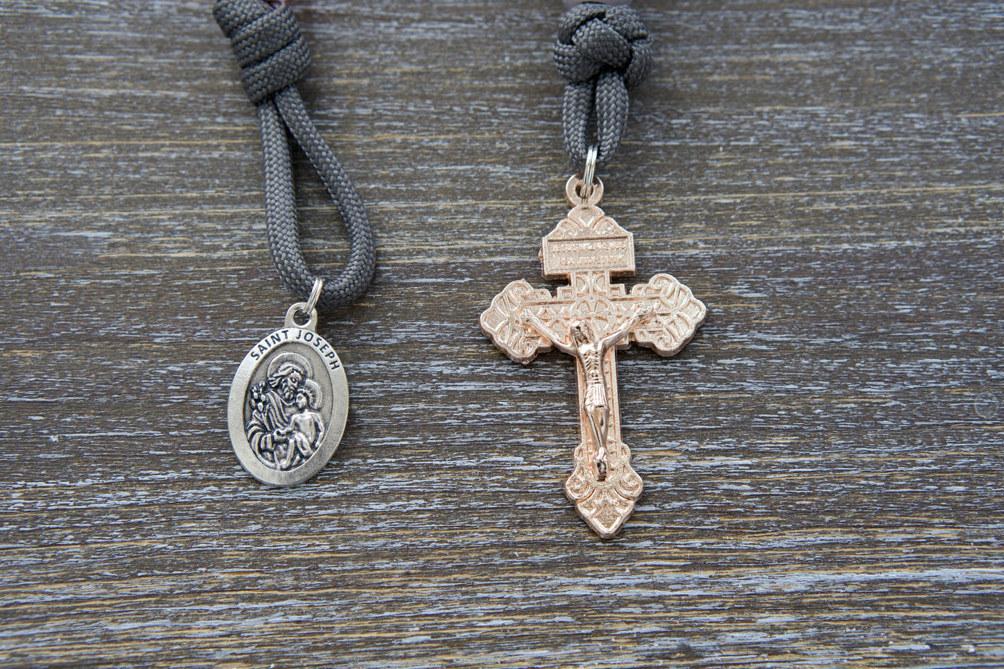 Pocket paracord rosary, "Ite Ad Joseph," featuring grey paracord, milky grey Our Father bead, contrasting milky pink Hail Mary beads, a rose gold Pardon Crucifix, and a St. Joseph devotional medal.