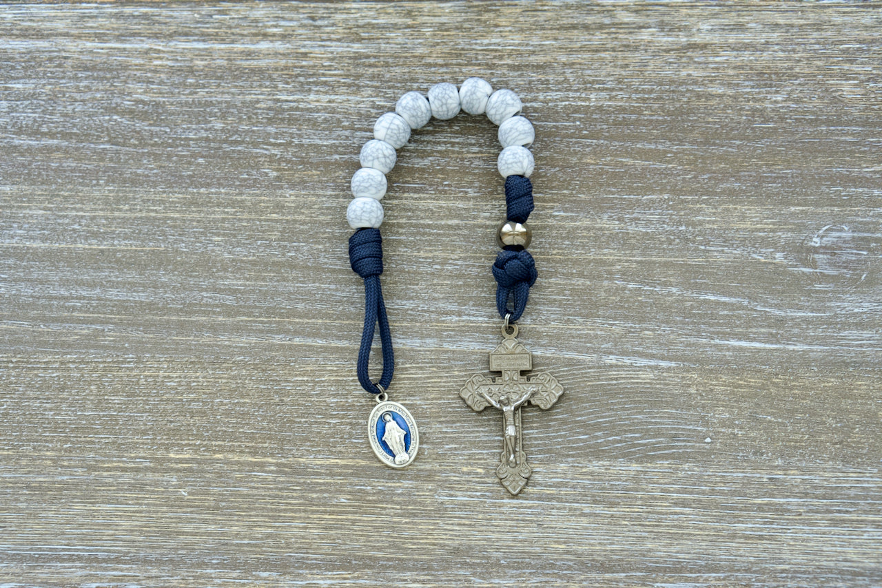 Premium Quality Marian Stronghold - Pocket Paracord Rosary with Navy Blue Rope, 12mm Acrylic Beads, Gunmetal Our Father Beads, Cracked Ivory Hail Mary Beads, and a 2-inch Pardon Crucifix. Durable Paracord 550 Construction, Complemented by a Blue Enamel Miraculous Medal.