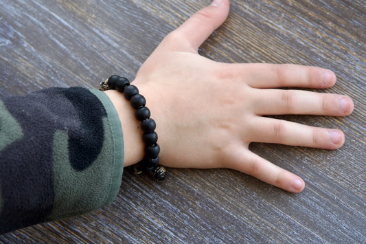 Rugged black acrylic rosary bracelet for kids featuring a Miraculous Medal and antique copper Our Father bead on durable paracord.