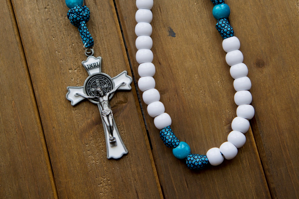 Embrace the power of Our Lady of Perpetual Help with this 5 Decade Turquoise Paracord Rosary! This unbreakable Catholic gift features a one-of-a-kind design, white Hail Mary beads, matching turquoise Our Father beads, and an impressive St. Benedict Crucifix.