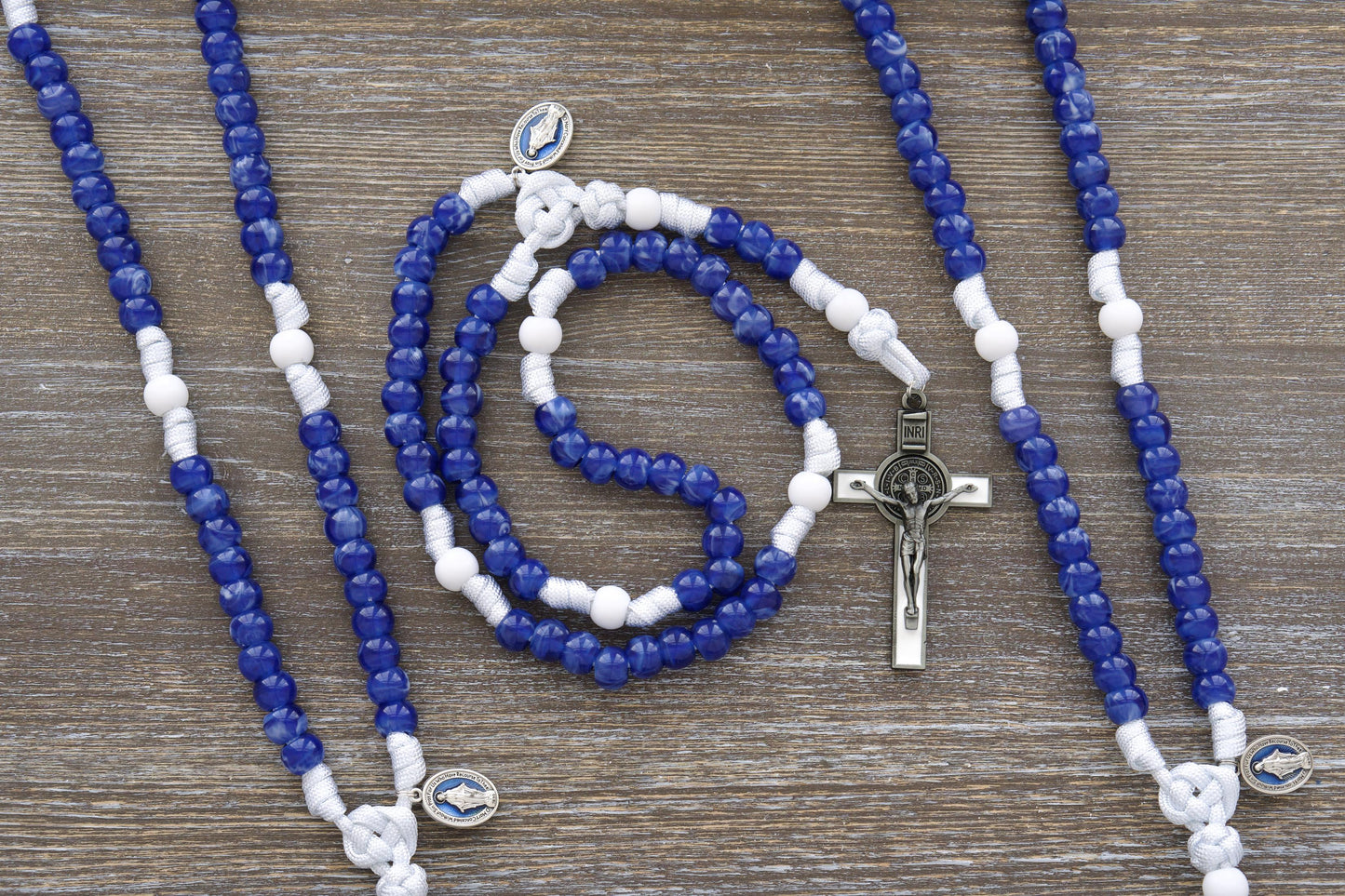 Our Lady's Mantle" 5 Decade Paracord Rosary: A handcrafted rosary featuring durable white paracord, a blue enamel Miraculous Medal, and a white enamel St. Benedict crucifix. Two distinct styles are available.