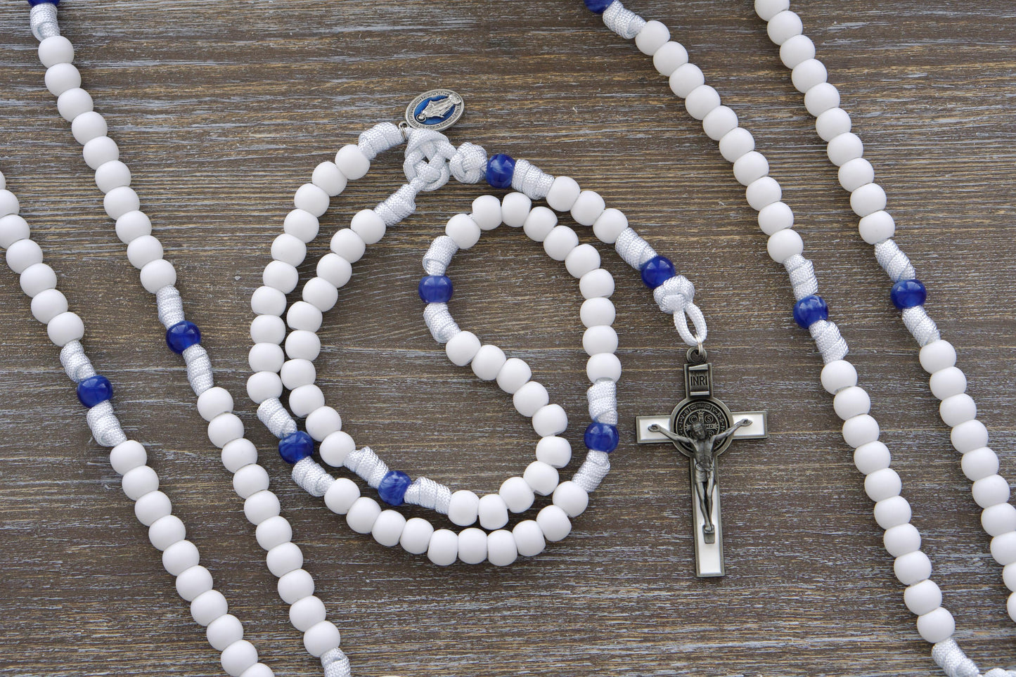 Our Lady's Mantle 5 Decade Rosary: Two stylish designs featuring white paracord, a blue enamel Miraculous Medal, and a white enamel St. Benedict crucifix. Choose from variations with matte white and milky miraculous blue 12mm acrylic beads