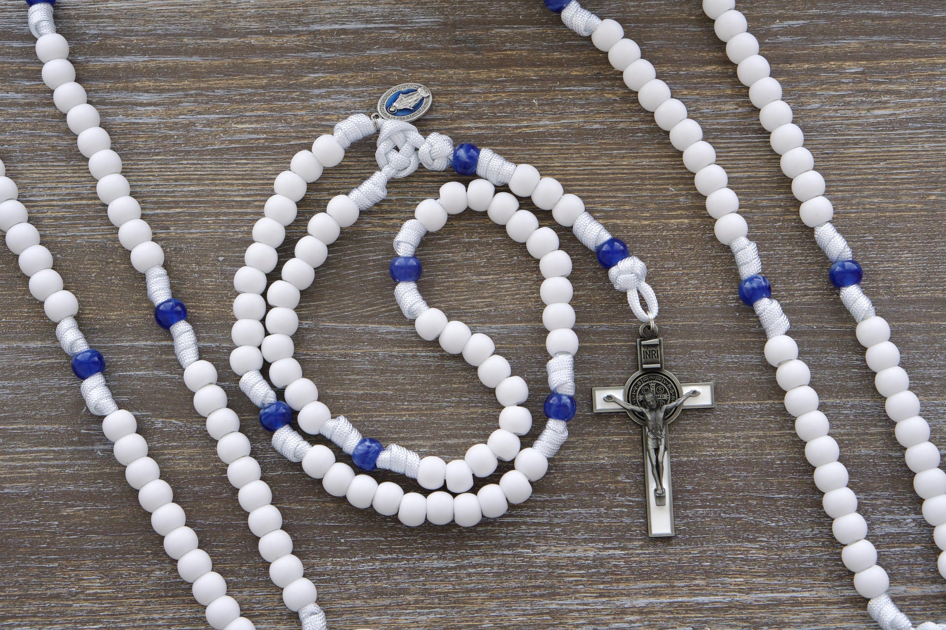 Our Lady's Mantle 5 Decade Rosary: Two stylish designs featuring white paracord, a blue enamel Miraculous Medal, and a white enamel St. Benedict crucifix.  Choose from variations with matte white and milky miraculous blue 12mm acrylic beads