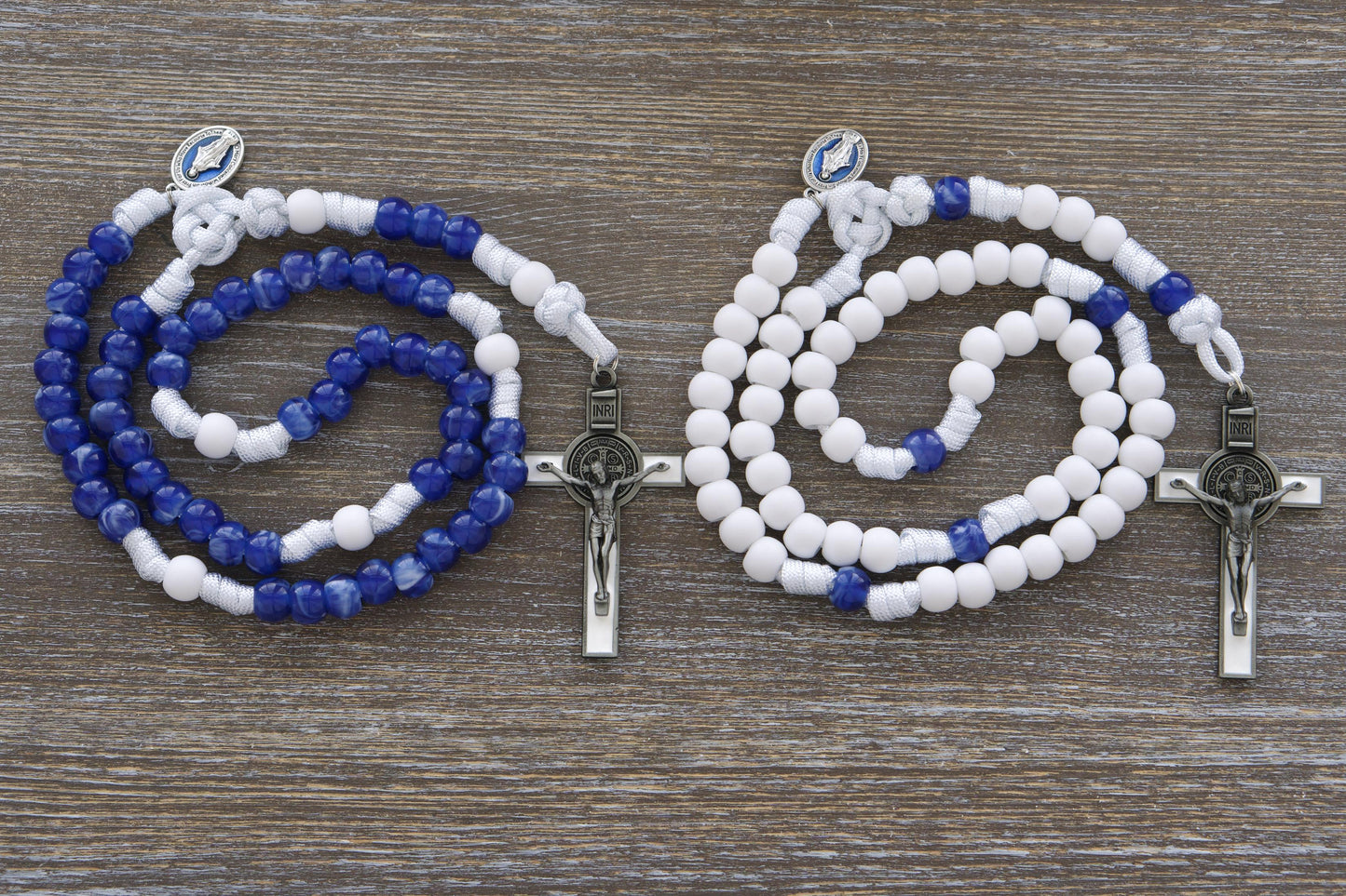 Strong white paracord rosary featuring a blue enamel Miraculous Medal and a white enamel St. Benedict crucifix. Available in two distinct styles with 12mm matte white and "miraculous blue" acrylic beads, honoring Our Lady's Mantle for spiritual protection and devotion. Handmade by Sanctus Servo.