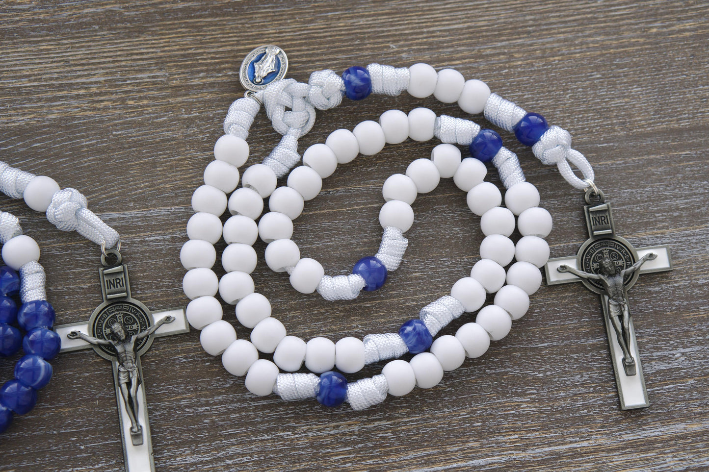 Handmade Our Lady's Mantle 5 Decade Rosary in two unique styles. Features sturdy white paracord, a blue enamel Miraculous Medal, and a white enamel St. Benedict crucifix.