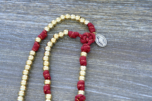 Scarlet Crown - Kid's 5 Decade Paracord Rosary with red paracord, gold beads, and a gold-ribbon finish, featuring a 2" gold Pardon Crucifix and a 1 inch Miraculous Medal for spiritual guidance and protection.