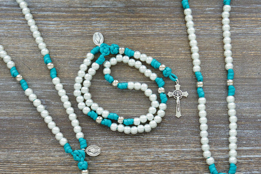 Teal blue paracord rosary with pearl Hail Mary beads, silver Our Father beads, and St. Benedict crucifix.