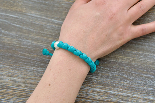 This teal blue paracord 550 Peaceful Waters rosary bracelet features a white 12mm Our Father bead, silver 10mm bead.