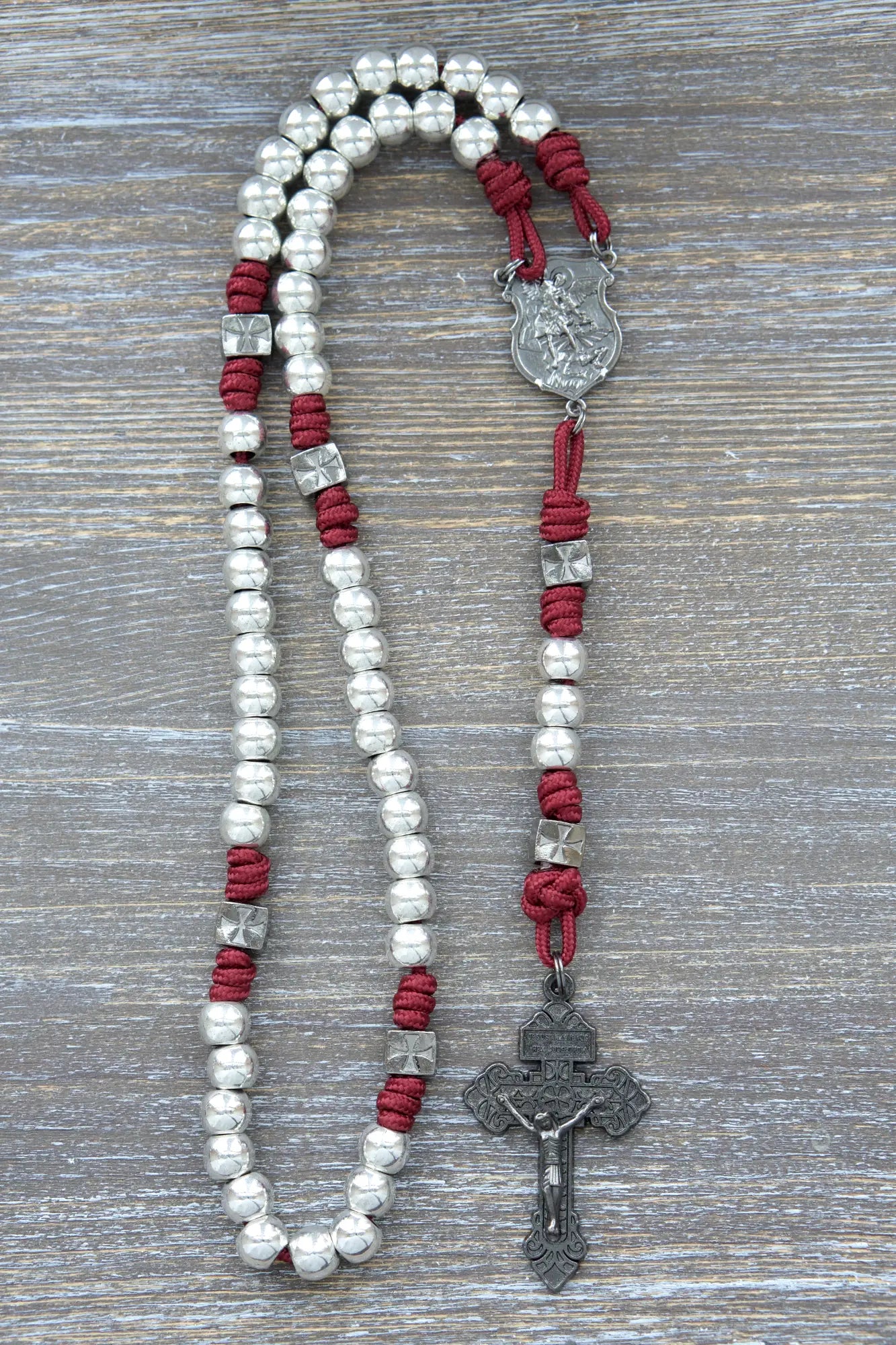 Metal paracord rosary with gunmetal St. Michael centerpiece, crucifix, and Hail Mary beads in iron crimson red rope color.