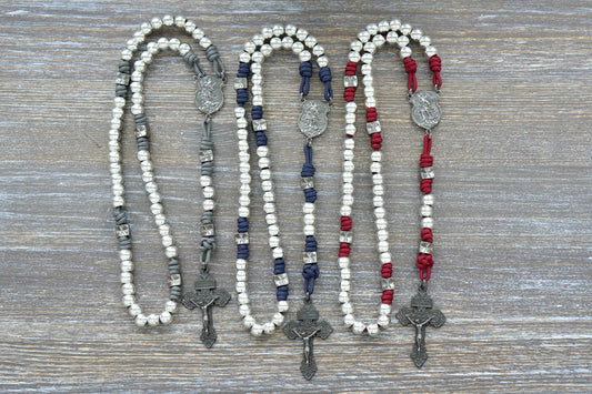 Three rosaries with white, blue, and red paracord rope and silver Hail Mary beads, gunmetal accents.
