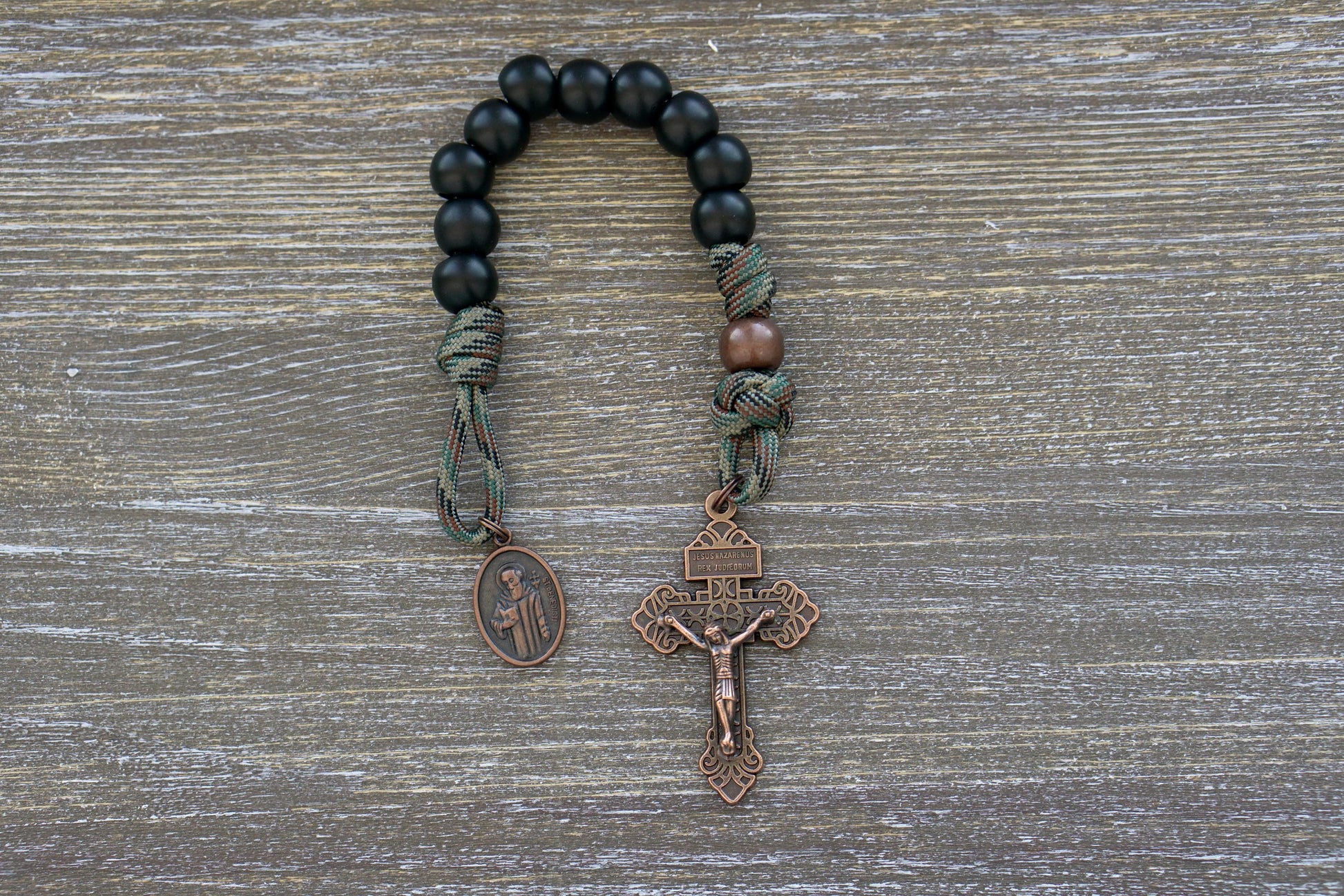 Camo paracord pocket rosary with antique copper Hail Mary beads, Our Father bead, crucifix adorned with a St. Benedict medal for protection against evil.  Designed for strength and devotion, perfect for everyday carry.