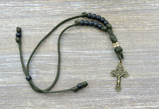 Green camo paracord rearview mirror rosary with matte black Hail Mary beads, an olive crusader Our Father bead, and an olive Pardon crucifix.