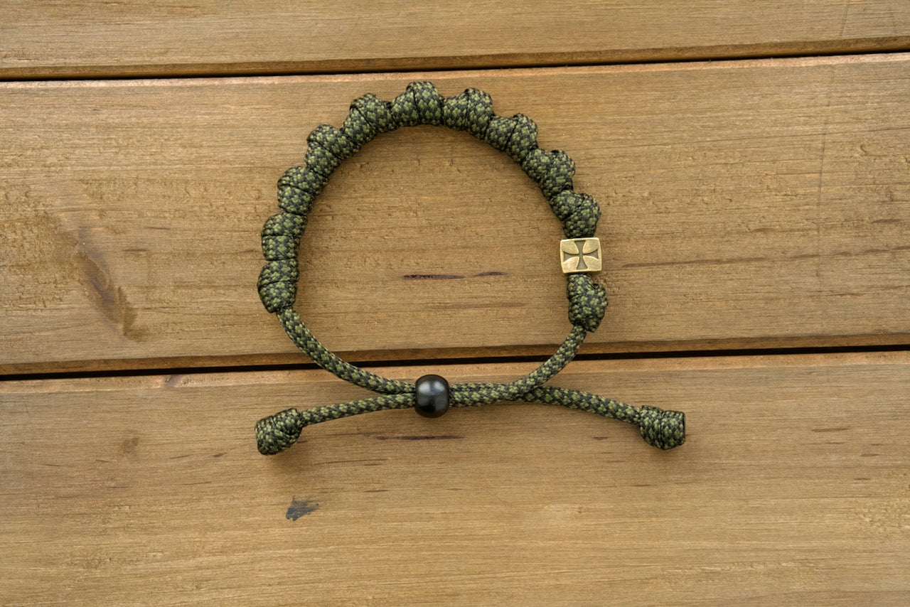 Durable olive metal alloy rosary bracelet with adjustable army green/black paracord, perfect for active Catholics seeking to strengthen their spiritual armor.