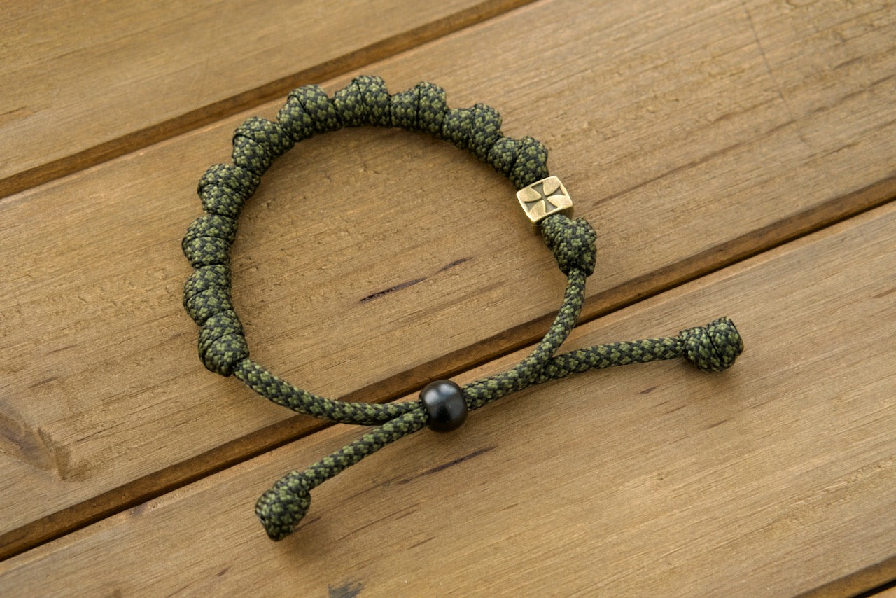 Durable olive metal alloy Shield of Faith - Rosary Bracelet featuring adjustable army green/black paracord rope, perfect for spiritual warriors on the go. Crafted with 10 Hail Mary knots and 5 decade full-size rosary pairing options. Unbreakable and comfortable for active lifestyles.