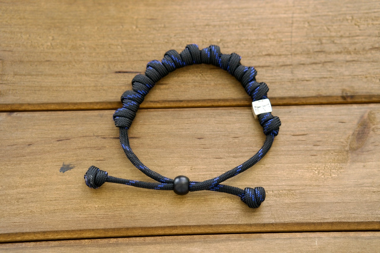 The Solemn Crusader - Rosary Bracelet, a premium unbreakable paracord rosary bracelet for Catholics. Strengthen your faith with this powerful spiritual weapon featuring black and blue paracord 550, silver Crusader Our Father bead, and traditional 10mm acrylic & 12mm metal alloy beads.