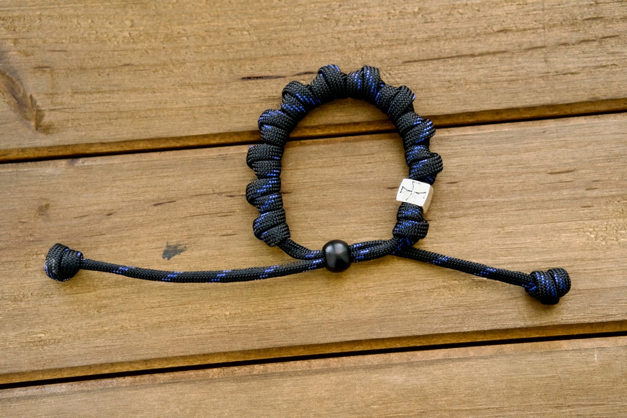The Solemn Crusader - Rosary Bracelet, a blend of traditional spirituality and modern durability. Premium paracord rosary bracelet with black and blue paracord 550, silver Crusader Our Father bead, acrylic & metal alloy beads for strength in faith.