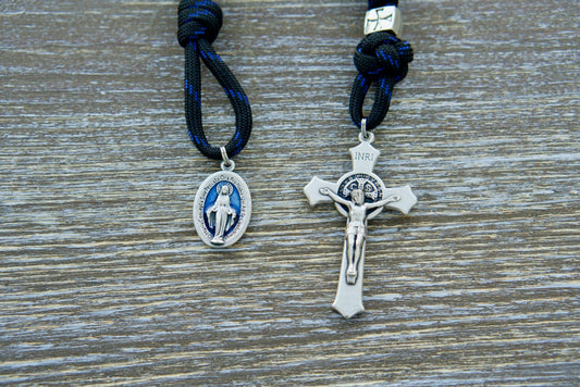 The Solemn Crusader - Blue Black and Silver 1 Decade Paracord Rosary: Embrace your unwavering devotion with this durable, premium, and unbreakable paracord rosary. Crafted for the modern-day crusader, this Catholic gift features black paracord, 12mm shiny black Hail Mary beads, silver metal alloy Our Father beads, a protective silver St. Benedict crucifix, and a blue enamel Miraculous Medal.