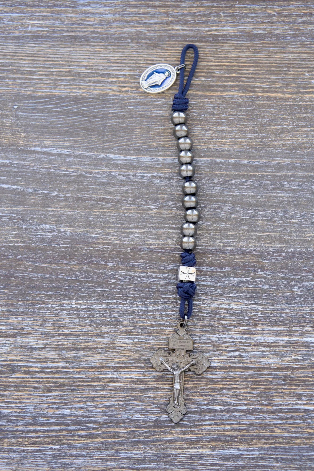 Solemn Crusader pocket paracord rosary with silver Our Father beads, gunmetal Hail Mary beads, and blue enamel Miraculous Medal centerpiece.
