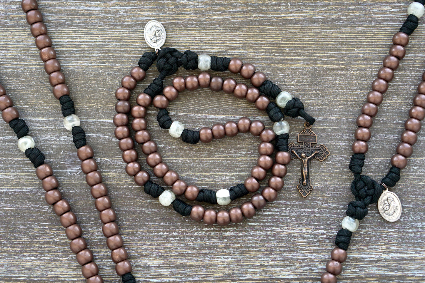 The Heretic Hammer - St. Anthony - 5 Decade Paracord Rosary: A stylish, durable rosary celebrating St. Anthony, the Hammer of Heretics, featuring black paracord, copper and pearl beads, St. Anthony devotional medal, and a Pardon Crucifix.