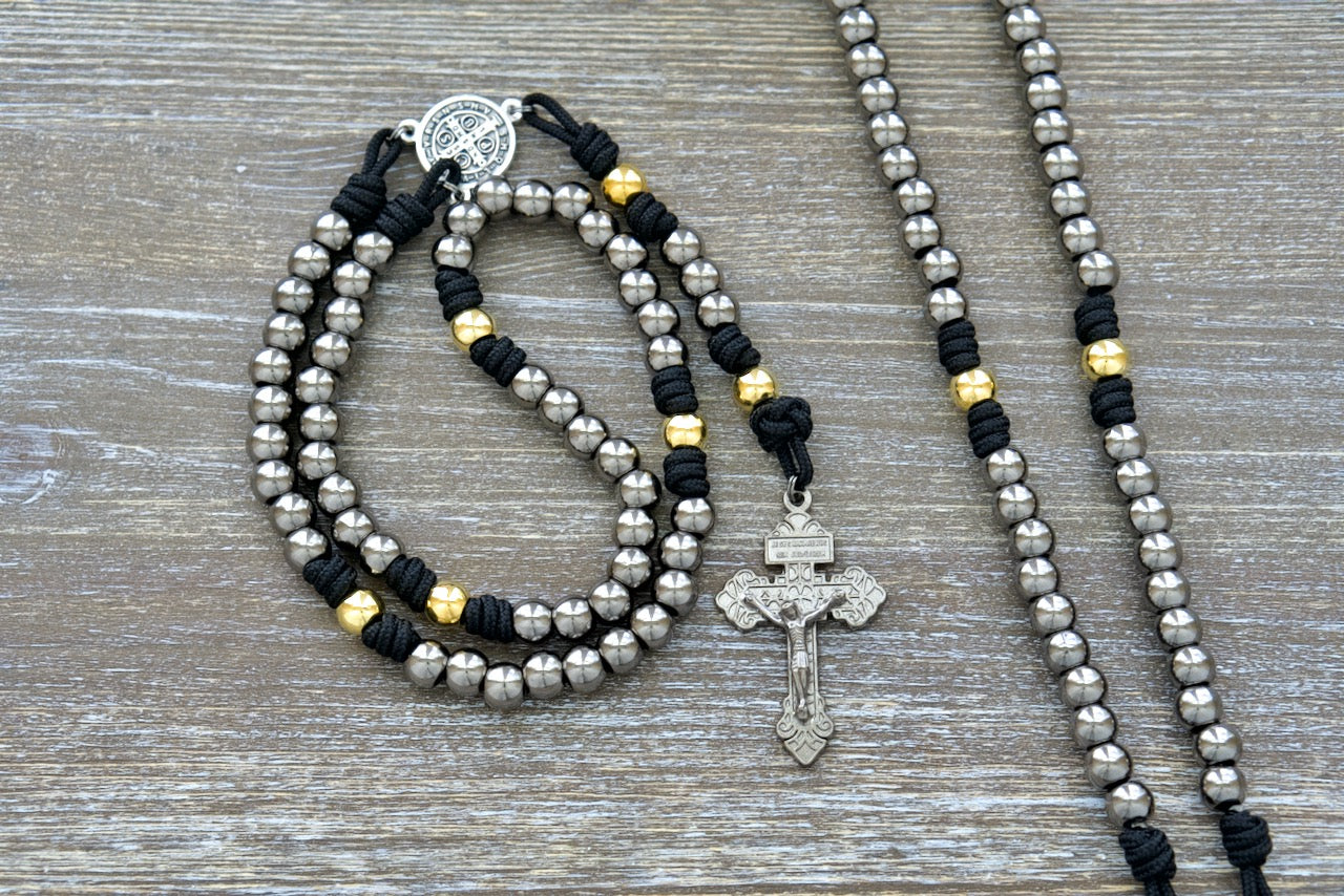 Stronghold of Grace | Gunmetal, Gold and Black | Premium Metal Rosary: Durable paracord rosary with gunmetal Hail Mary beads, gold Our Father beads, St. Benedict center devotional medal, and 2-inch Pardon crucifix.