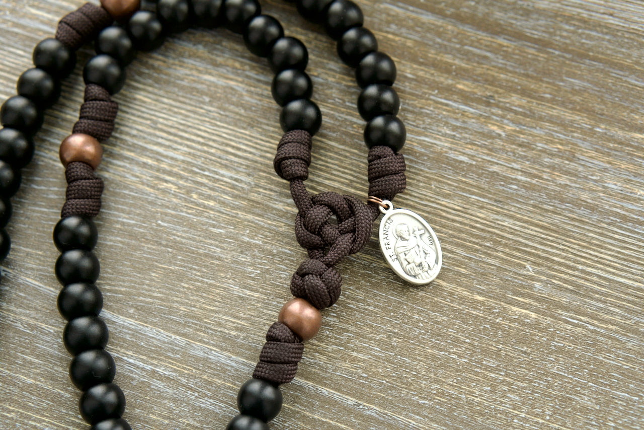 The Franciscan Forge - St. Francis - 5 Decade Paracord Rosary, handcrafted by a Catholic family of six with durable brown paracord and antique copper Our Father beads; featuring a St. Francis devotional medal, rustic copper 'triple threat' pardon crucifix, and premium materials for your spiritual journey.