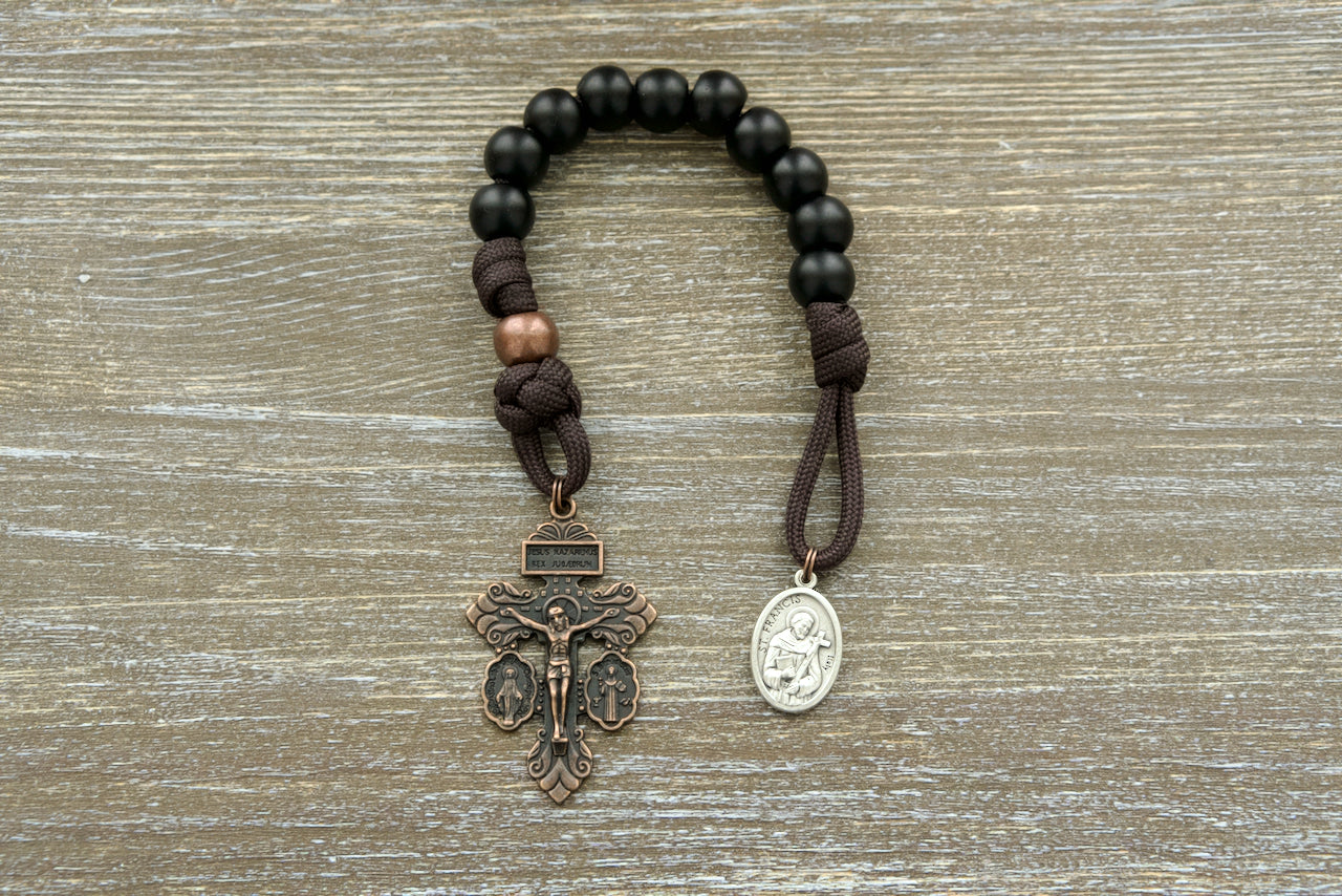 The Franciscan Forge St. Francis Pocket Paracord Rosary - Handmade with durable, premium brown paracord, copper Our Father beads, and matte black Hail Mary beads; featuring a devotional medal of St. Francis and a 2-inch Triple Threat crucifix for unbreakable Catholic prayer on-the-go!