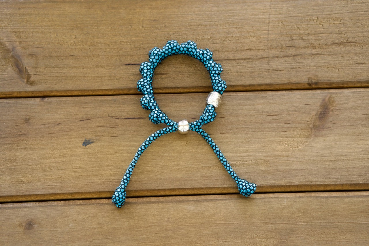 Experience divine spirituality in a modern package with the Turquoise & Silver Rosary Bracelet from Sanctus Servo. This exquisite Catholic accessory features premium paracord construction, turquoise and black design elements, and a silver Our Father bead for added elegance and strength.