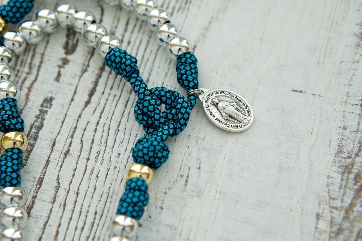 Embrace the unbreakable bond with this Turquoise and Silver 5 Decade Paracord Rosary - an indestructible weapon for your spiritual battles. Featuring a Miraculous Medal and premium materials, our handmade rosaries are perfect for Catholic devotees of all ages.