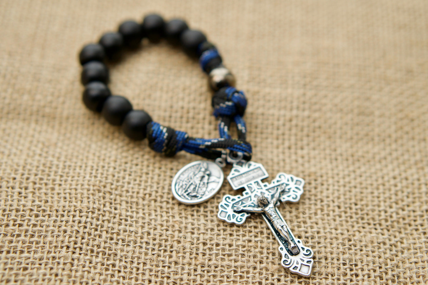 Join the ranks of LEOs with our Thin Blue Line - 1 Decade Paracord Rosary. Featuring St. Michael as the Devotional Medal and gunmetal access bead, this durable, premium paracord rosary is perfect for your pocket, ensuring you're always ready to fight on the spiritual battlefield.