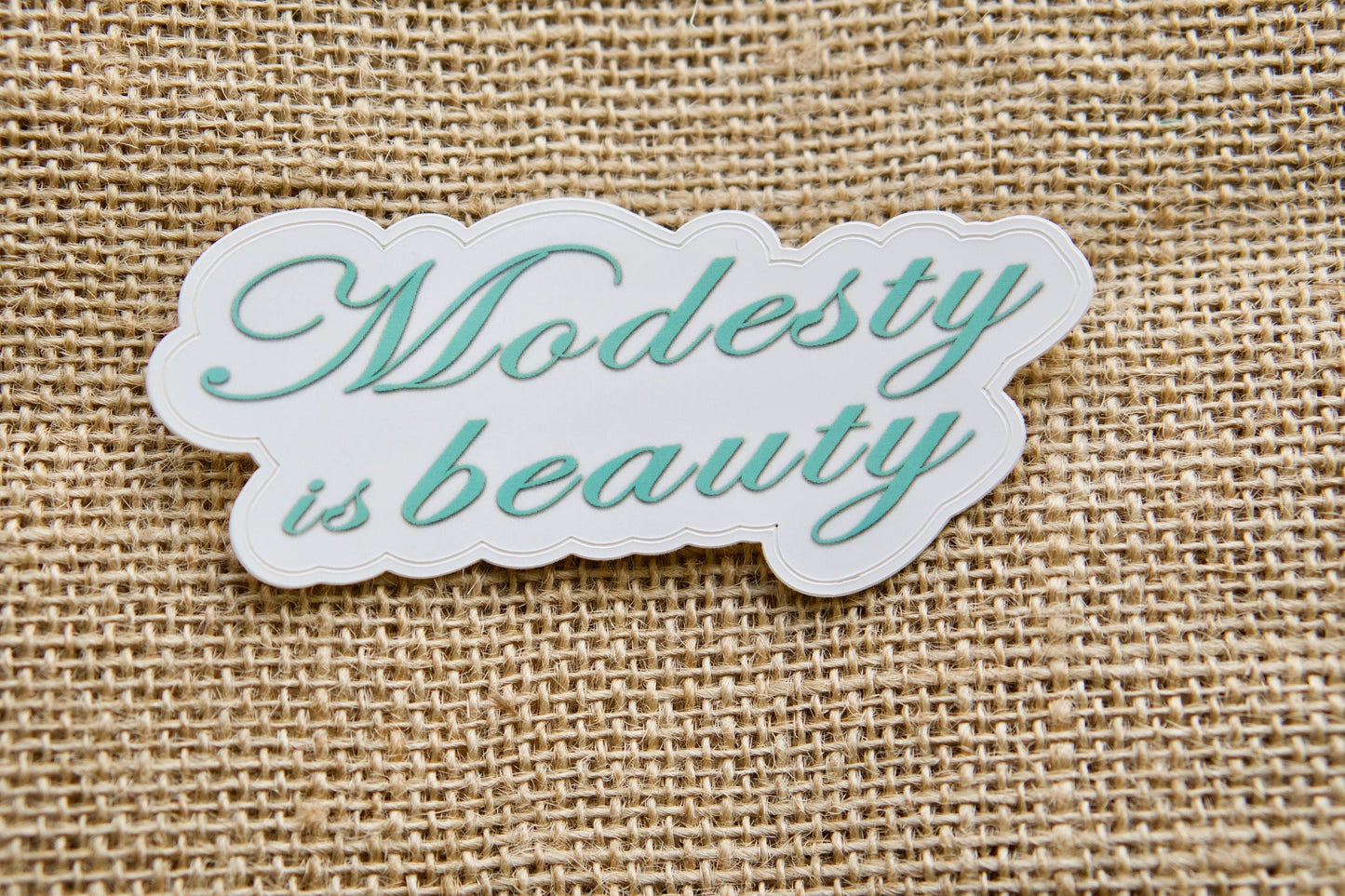 Modesty is Beauty - Spread the message of true beauty through simplicity with this 4" x 2" vinyl sticker, perfect for laptops, water bottles, notebooks or any other surface. Pair it with a rosary for an inspiring combination and make it a thoughtful stocking stuffer.