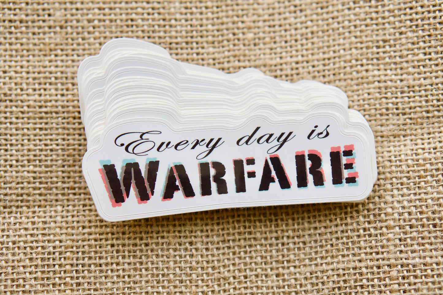 Vinyl Sticker - Every day is WARFARE: Spread the message of Christian battle and faith with this powerful 4" x 1.5" sticker, perfect for laptops, water bottles, notebooks, and more! Pair it with a rosary for an inspiring gift or stocking stuffer.