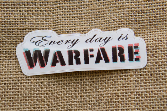 Every day is WARFARE - Vinyl Sticker: Take up your cross, fight the spiritual battle, and spread the message. Measuring 4" wide and 1.5" tall, this durable sticker is perfect for laptops, water bottles, notebooks, or anywhere you need a reminder to stand strong in faith.