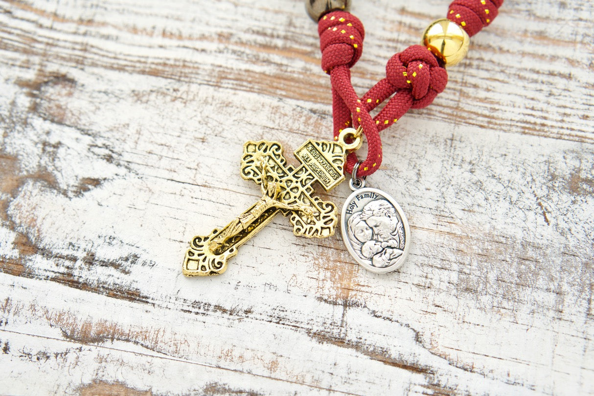 The Holy Family - 1 Decade Paracord Rosary, a durable and powerful spiritual weapon for prayer, featuring royal red, gold, and gunmetal design with an antique gold Pardon crucifix and double-sided Holy Family/St. Joseph medal. Handmade by a small Catholic family of 6, rigorously tested for kids and guaranteed not to break.
